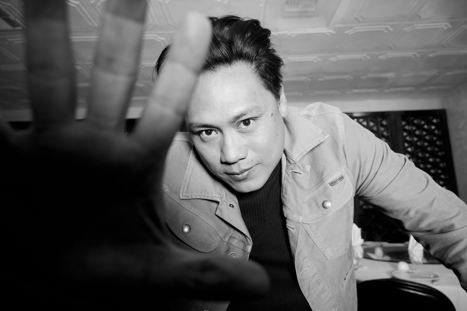 Image may contain Jon M. Chu Body Part Finger Hand Person Face Head Photography Portrait Clothing Coat and Adult