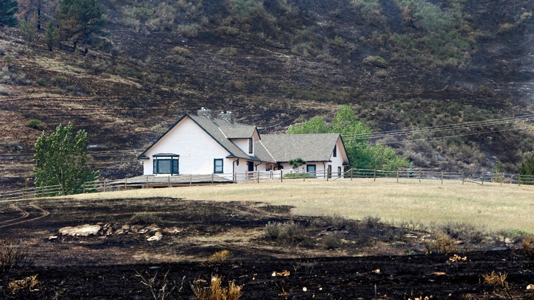 A house is surrounded by burned grass