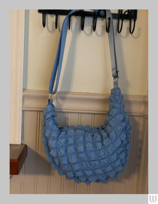 Blue puffy crossbody bag hanging from wall hooks