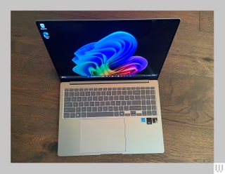 Topdown view of opened silver laptop showing the keyboard and abstract art on thes screen