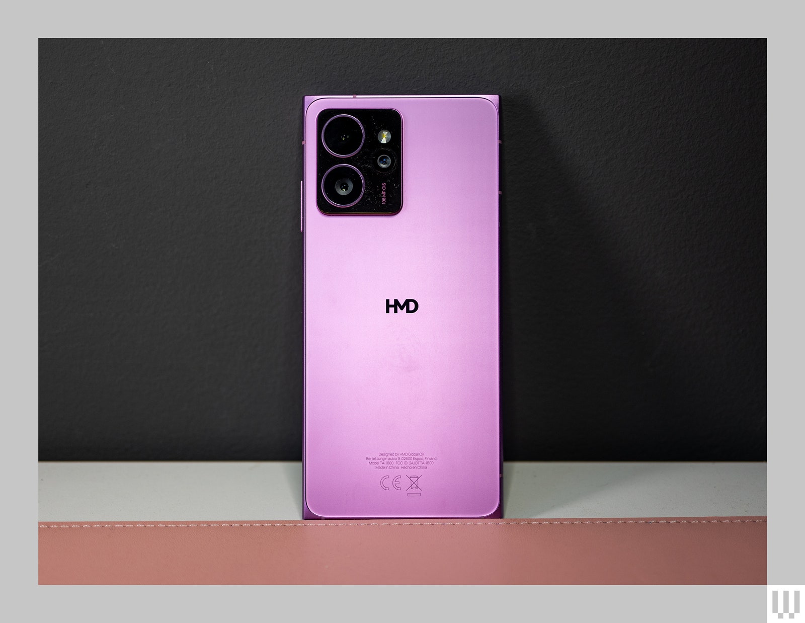 Pink mobile phone propped up against the wall showing it's rear cameras