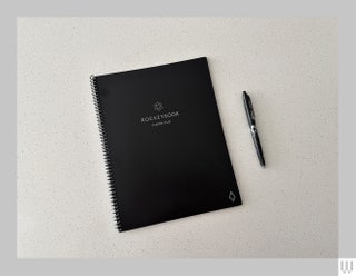 Black digital notebook with a black pen on white surface