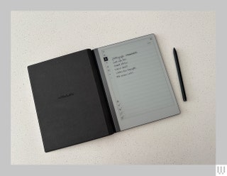 Digital notebook open and flat on a white surface with the digital pen beside it