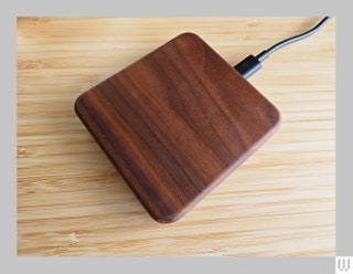 Square wooden wireless phone charger sitting on a wooden surface