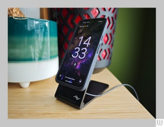 Black angular wireless charger propping up a phone near the edge of a table