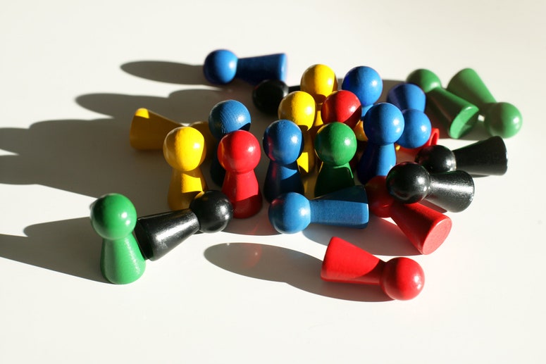 Red, yellow, blue, green, and black wooden game pieces in a pile with dramatic lighting