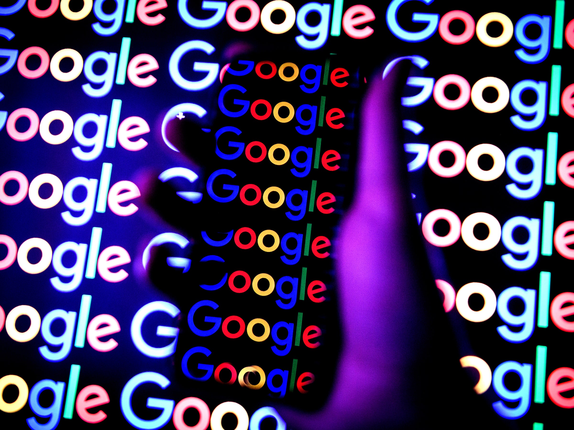 Google logos and a person holding a smartphone