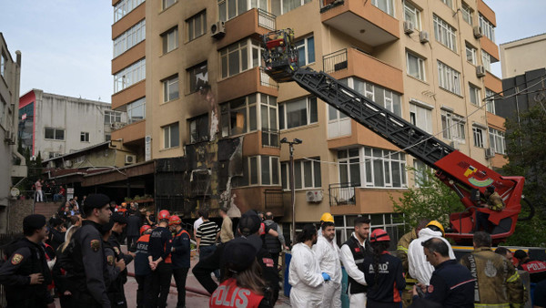 Rettungskräfte stehen nach dem Brand vor dem Gebäude.