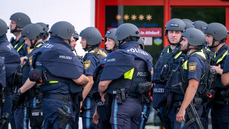Zahlreiche Polizisten stehen zu einer Besprechung zusammen. Nach einem Brand mit „Bedrohungslage“ hatte die Polizei in Altdorf bei Nürnberg bei der Fahndung nach einem bewaffneten Mann ein Waldstück umstellt.