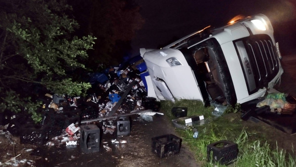 Verstreute und kaputte Bierkästen liegen neben dem umgekippten Lkw auf der A10