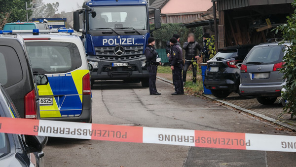 Einsatzkräfte der Polizei stehen an einem Grundstück, auf dem eine Leiche geborgen wurde.