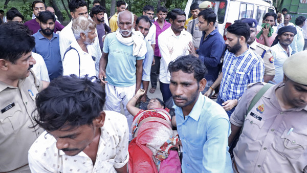 Nach der Massenpanik tragen Menschen in Indien eine Frau auf einer Bahre.