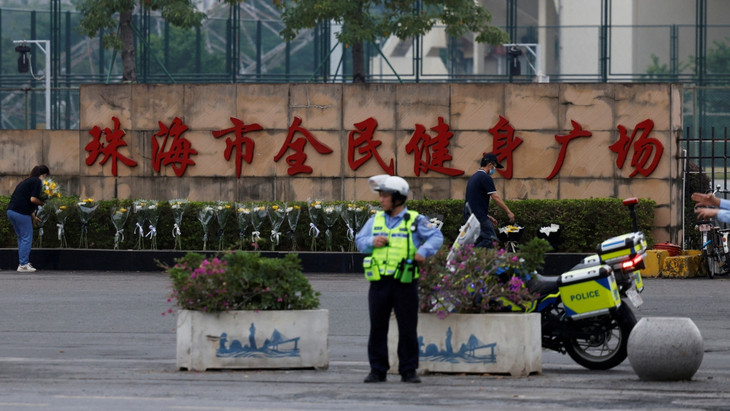 Nach der tödlichen Attacke in Zhuhai legen Menschen Blumen nahe des Tatorts ab, ein Polizist steht Wache.