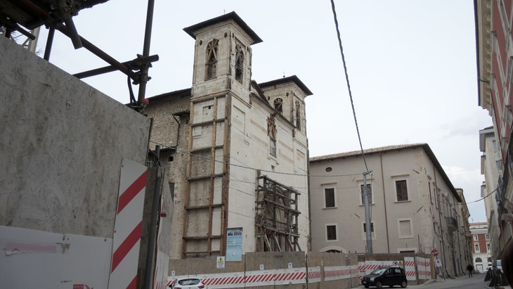 Blick auf eine Kirche in L'Aquila, die im Jahr 2019 – zehn Jahre nach dem Erdbeben – noch immer einer Baustelle gleicht.
