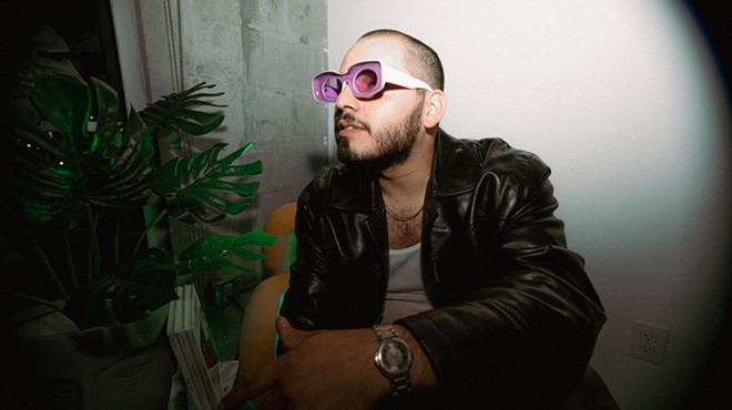 man posing with pink and white sunglasses and a black jacket