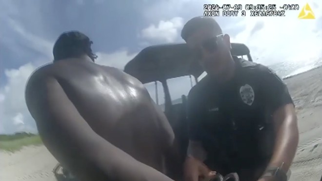 body cam screenshot of a police officer cuffing a suspect on a beach