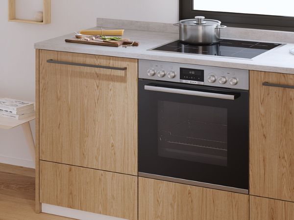 Water boiling on a built-in cooker next to a cutting board with all the ingredients for a simple yet delicious spaghetti aglio e olio