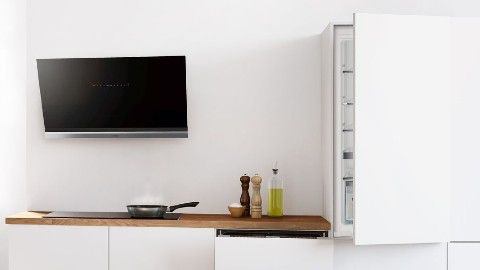 White kitchen with an oak counter, a high-tech hood and built-in kitchen appliances. Olive oil and spices on the counter