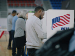 Elderly male voter with bulletin in hands comes to voting booth