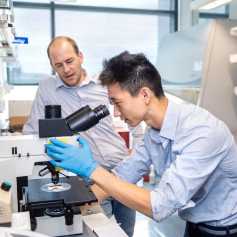 faculty and student looking into a microscope