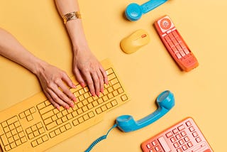 Hands typing on a keyboard surrounded by telephones