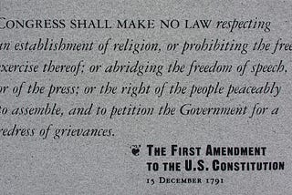 A photograph of a stone plaque engraved with the First Amendment to the United States Constitution