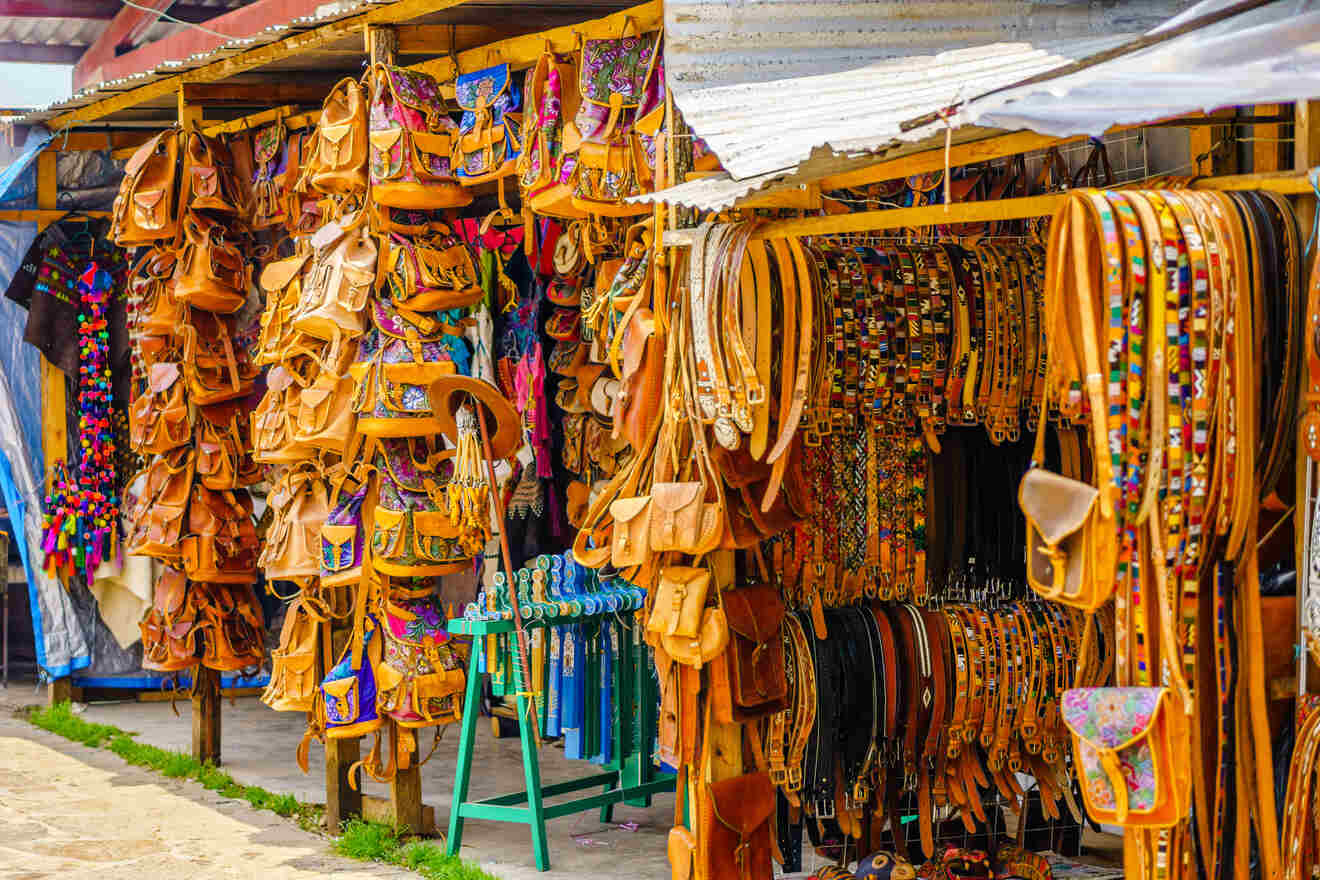 Stall displaying various leather goods, including bags, belts, and hats.