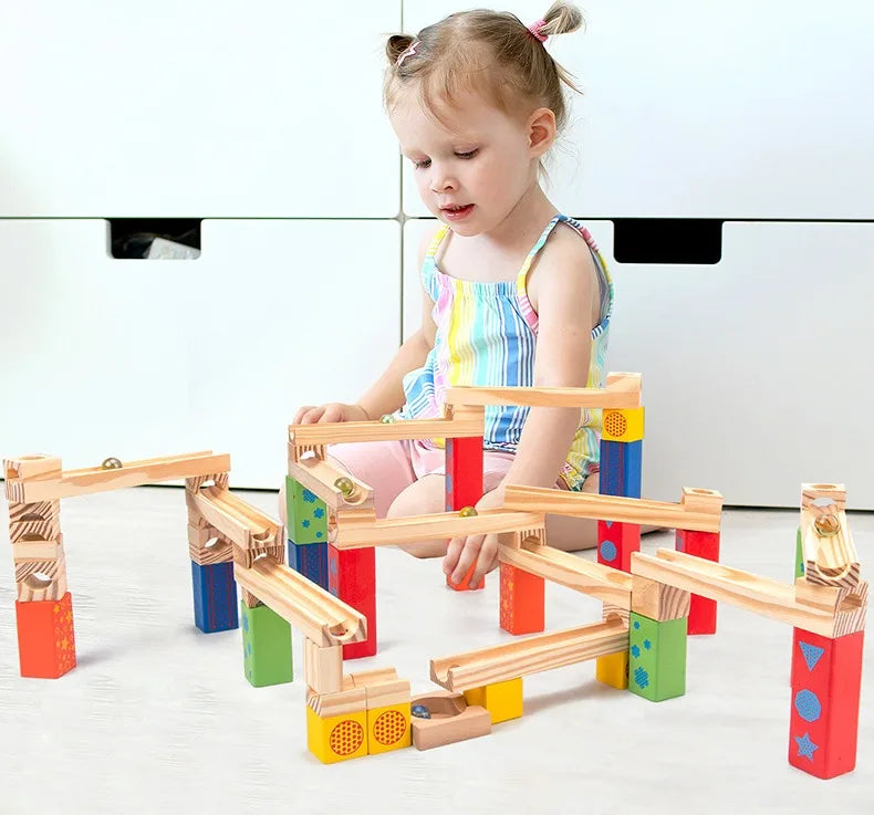 Little girl sitting on the floor and playing with her Montessori Wooden Marble Run.