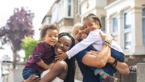 Happy family with two kids stands outside their apartment.