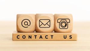 A rectangular wooden block with the words "Contact Us." Resting on top of that are three cubic wooden blocks. Each has an icon representing a contact method: An @ symbol, an email envelope, and a telephone.