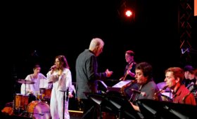 Jazz students perform onstage led by conductor.