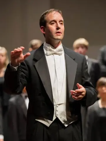 Dr. Cristian Grases conducting in concert attire.