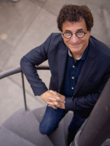 Photo of Robert Cutietta standing on a spiral staircase looking up at the camera.