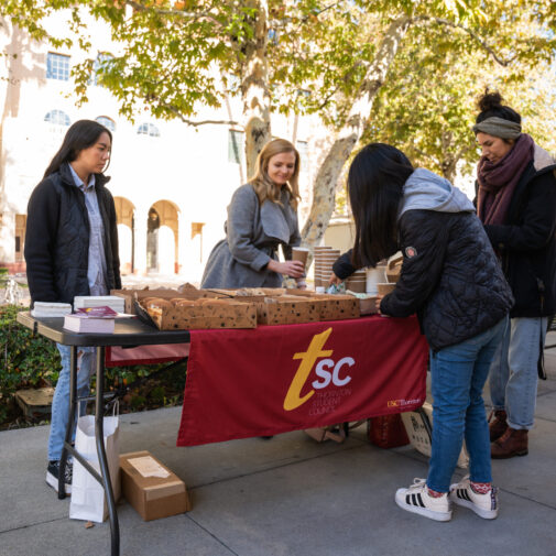 students gathered around an information table with breakfast treats.