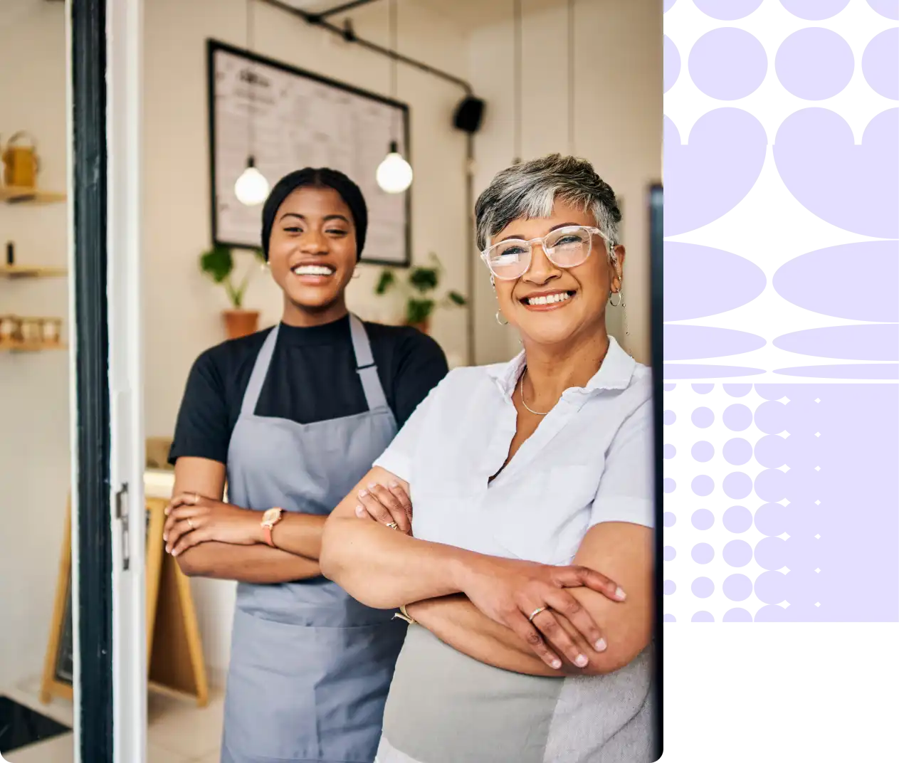 Two women standing with arms folded leaning on a storefront doorway