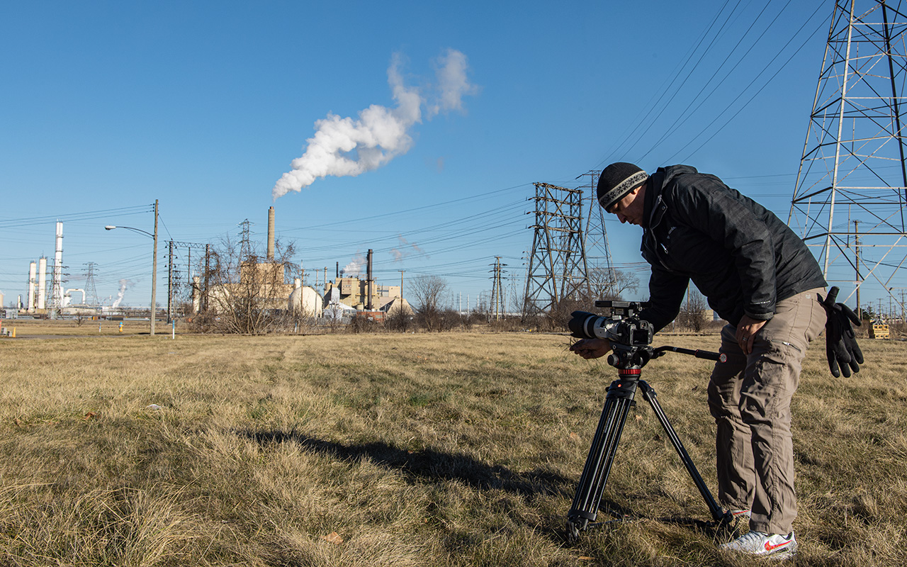 A student adjusts a camera while filming a factory