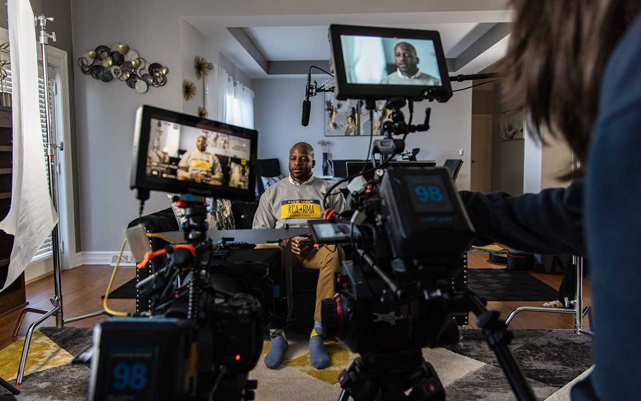 A man is interviewed in a house surrounded by video equipment