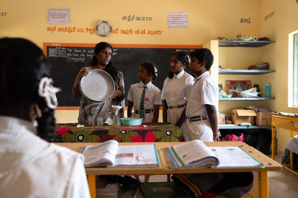 A female teacher demonstrating a science experiment to students in a classroom