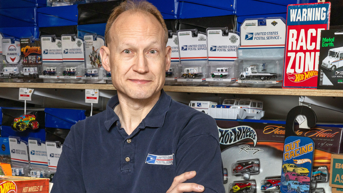 A man stands in front of a display of miniature toy vehicles