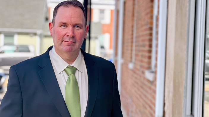 A man wearing a dark blue suit and lime green tie