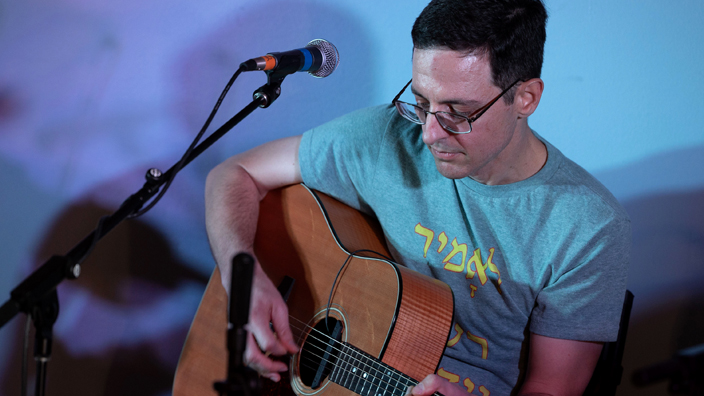 Man plays guitar near microphone