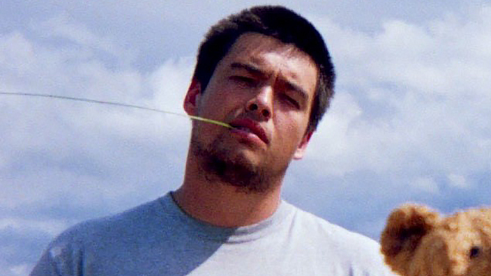 Young man in T-shirt stands outdoors