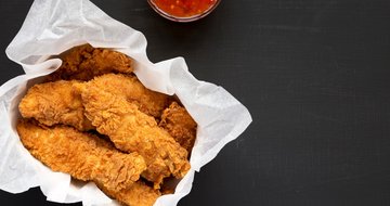 chicken tenders with sour-sweet sauce on a black background, top view