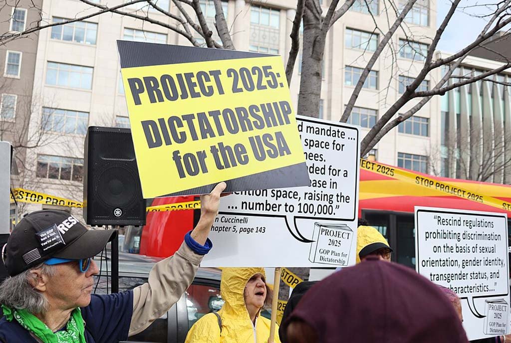 Image of an active protest with a protester holding a sign reading "Project 2025: Dictatorship for the USA"