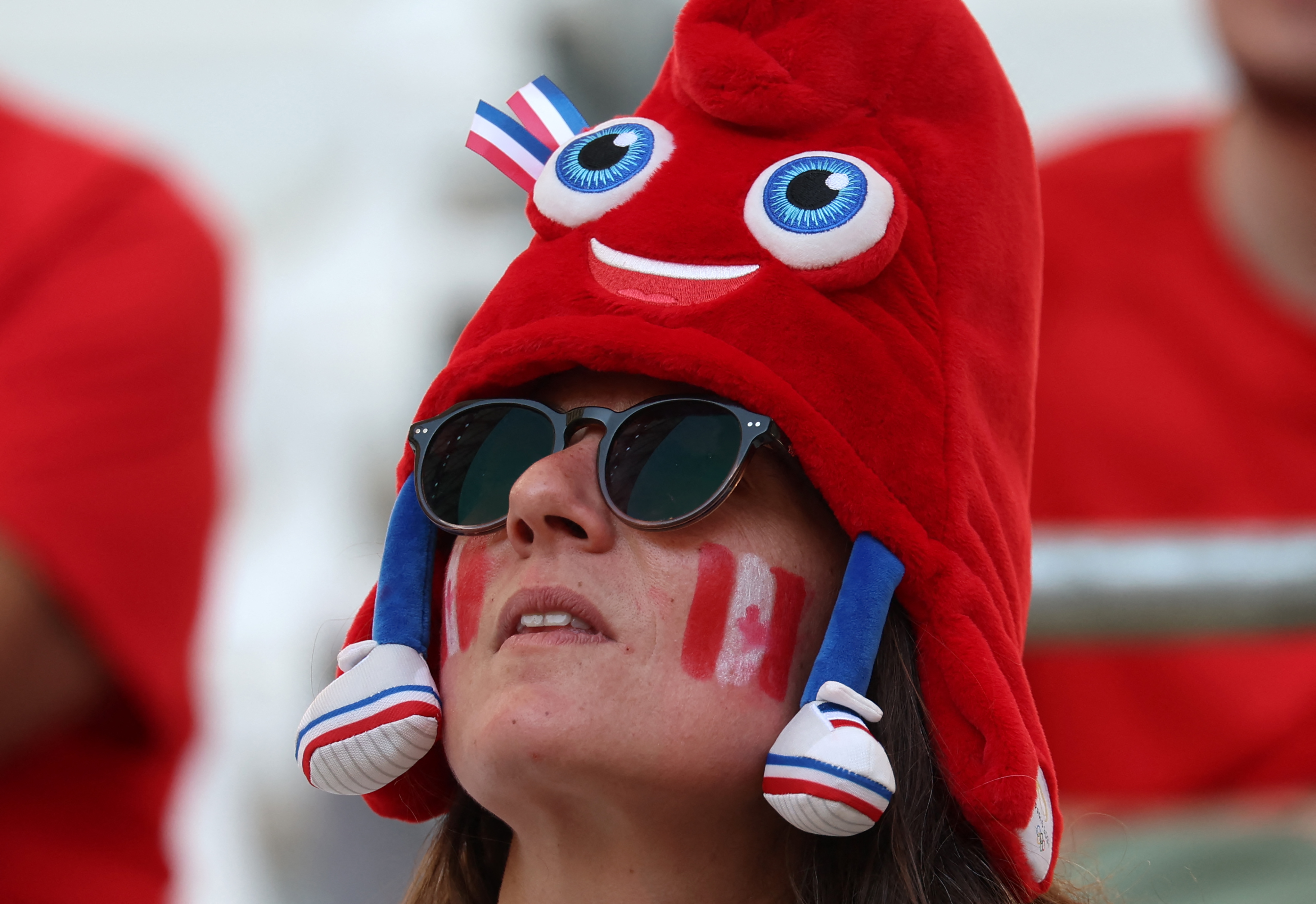 A Canada fan dons an Olympic mascot Phryge hat before the women's quarter-final football match between Canada and Germany during the Paris Olympics.