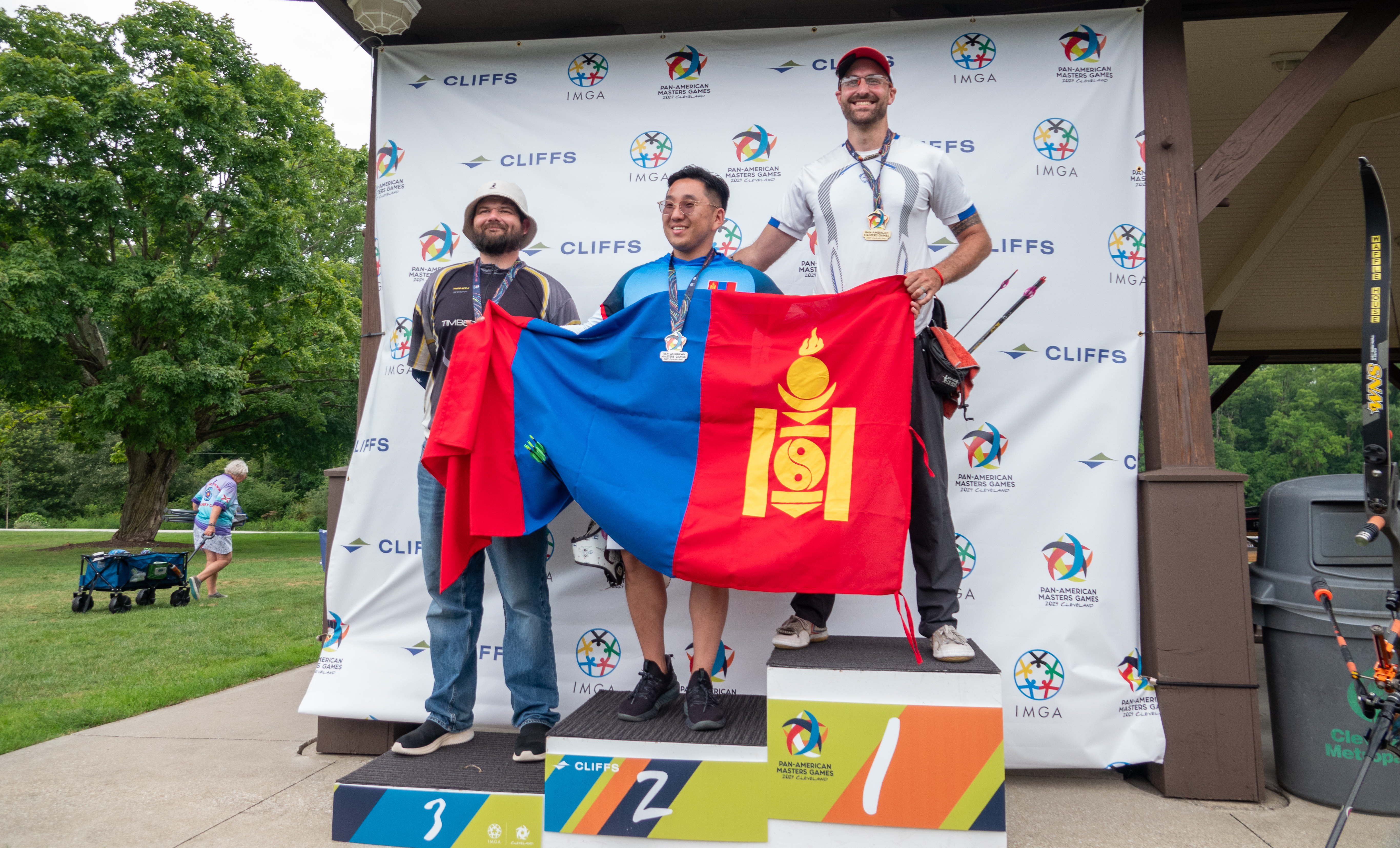 three men pose for pictures on medal podium at competition