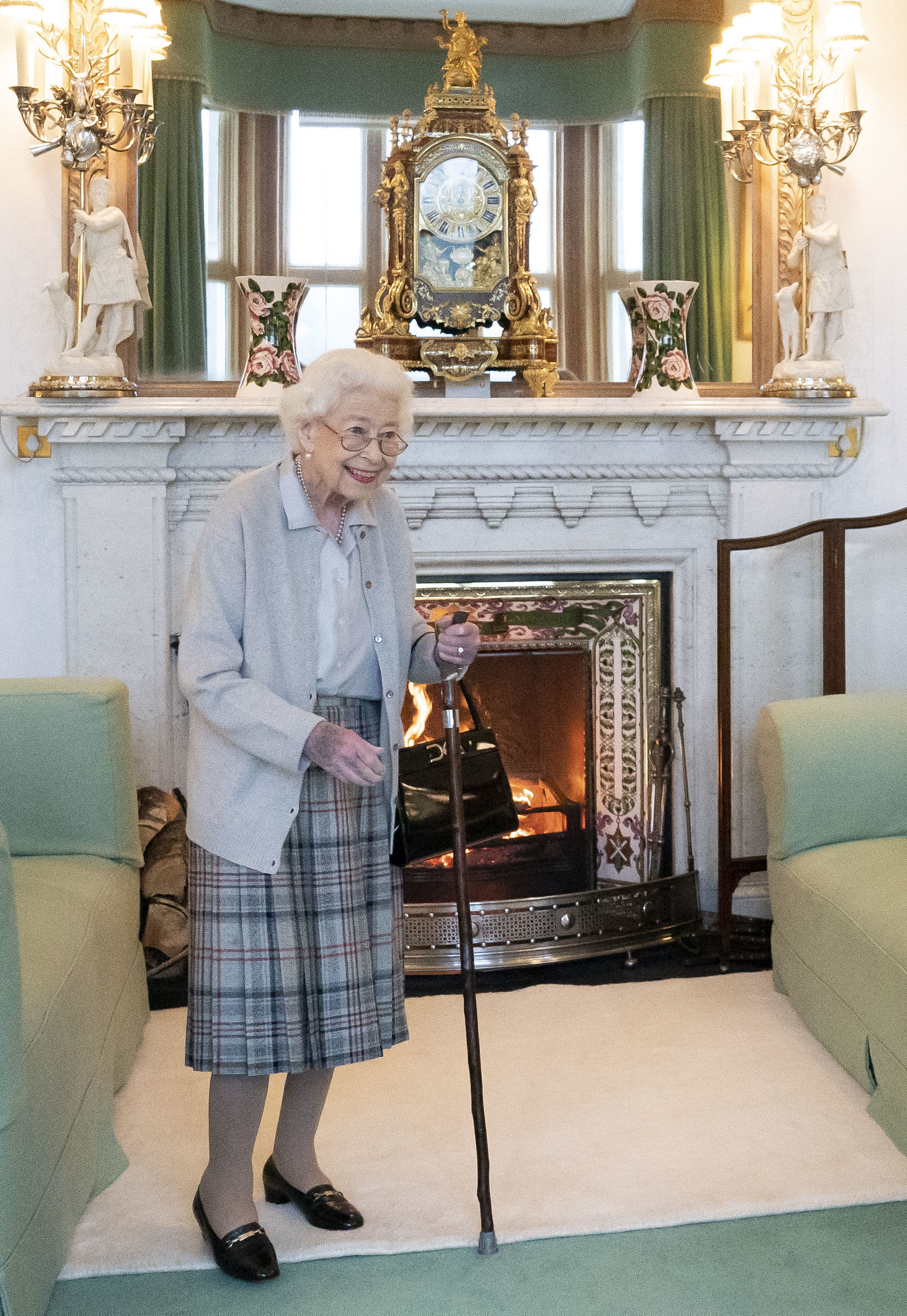 Queen Elizabeth smiles while standing in a green and gold room, in the last publicly-released photo taken of her before her death on Thursday.