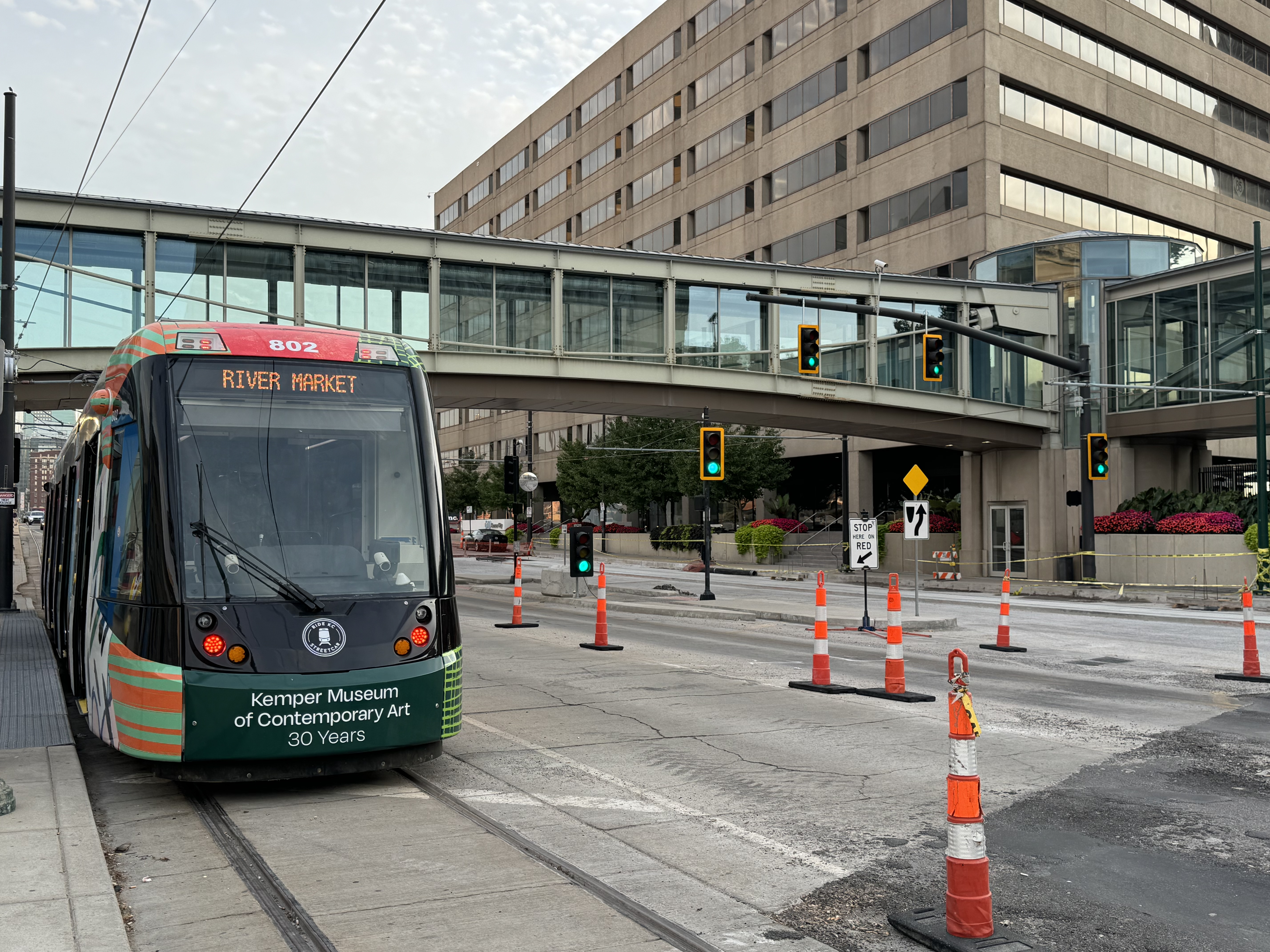 A streetcar is stopped on a street with orange construction cones. 