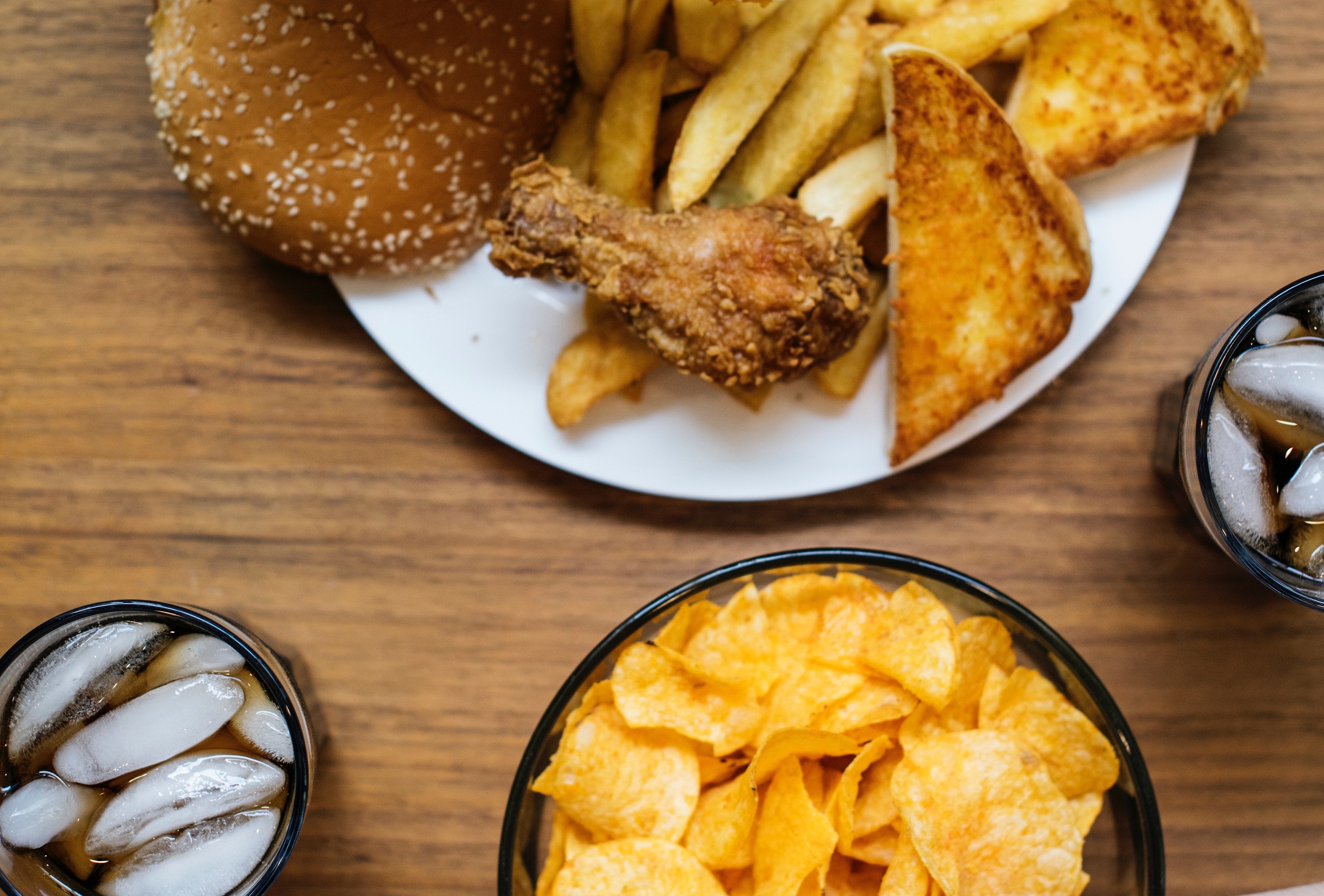 a plate of soda, chips, fried chicken, grilled cheese, hamburgers, french fries