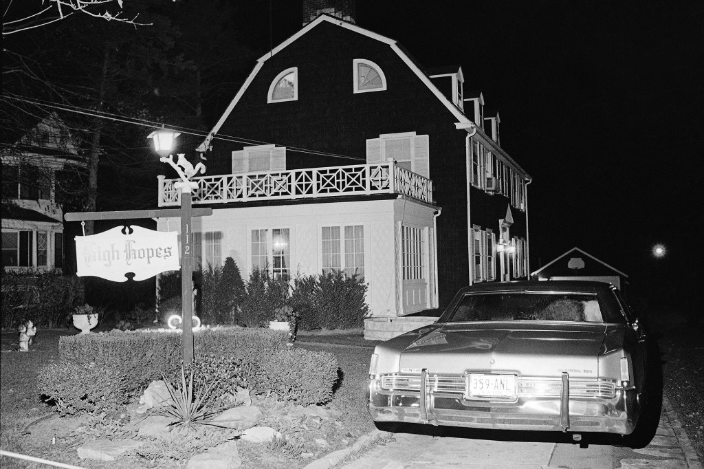 In this Nov. 14, 1974 file photo, police and members of the Suffolk County Coroner's Office investigate the murder of six people found shot in Amityville, N.Y. 